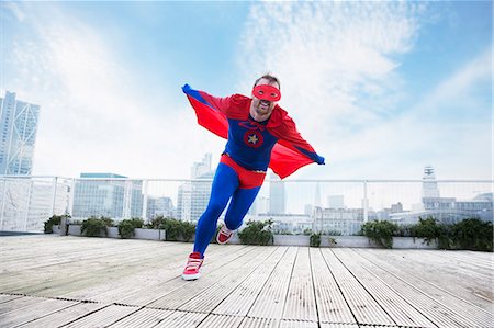 funny characters or funny cartoons - Superhero running with cape on city rooftop Stock Photo - Premium Royalty-Free, Code: 6113-07961675