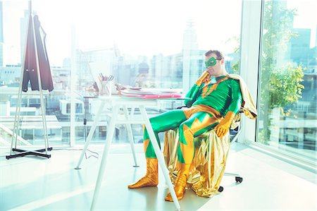 Bored superhero slouching at desk in office Foto de stock - Sin royalties Premium, Código: 6113-07961679