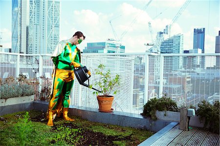 responsible man - Superhero watering potted plant on city rooftop Stock Photo - Premium Royalty-Free, Code: 6113-07961683