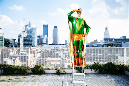 Superhero overlooking view from stepladder on city rooftop Stockbilder - Premium RF Lizenzfrei, Bildnummer: 6113-07961707