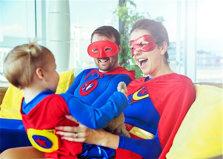 family masks - Superhero parents playing with daughter on living room sofa Stock Photo - Premium Royalty-Free, Code: 6113-07961708