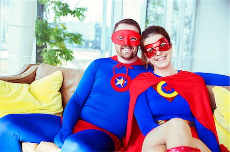 simsearch:6113-07961715,k - Superhero couple smiling on living room sofa Foto de stock - Sin royalties Premium, Código: 6113-07961710