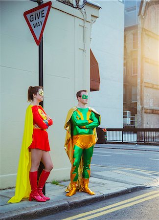 Superhero couple waiting at corner on city sidewalk Stock Photo - Premium Royalty-Free, Code: 6113-07961723