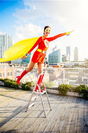 flying happy woman images - Superhero standing on stepladder on city rooftop Photographie de stock - Premium Libres de Droits, Code: 6113-07961728