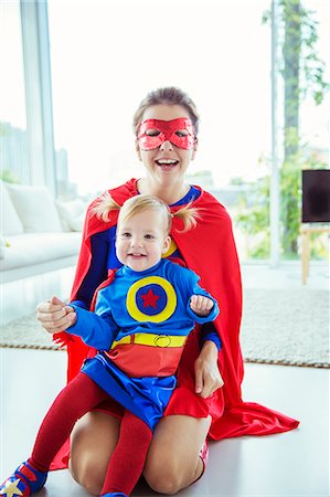 força - Superhero hugging daughter on living room floor Foto de stock - Royalty Free Premium, Número: 6113-07961737