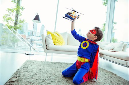 Superhero boy playing with toy helicopter in living room Stock Photo - Premium Royalty-Free, Code: 6113-07961739