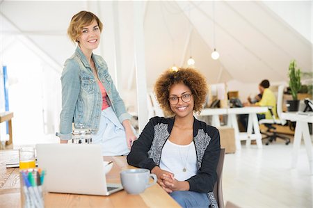 simsearch:6113-07991890,k - Portrait of women smiling in office with laptop on desk Stock Photo - Premium Royalty-Free, Code: 6113-07991868