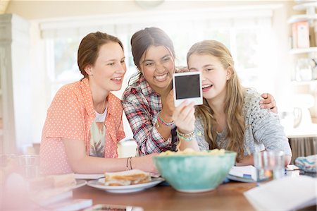 Three teenage girls looking at photograph while sitting at table Stock Photo - Premium Royalty-Free, Code: 6113-07991993
