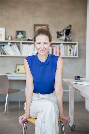 Portrait of young woman sitting on stool in studio Stock Photo - Premium Royalty-Free, Code: 6113-07992087