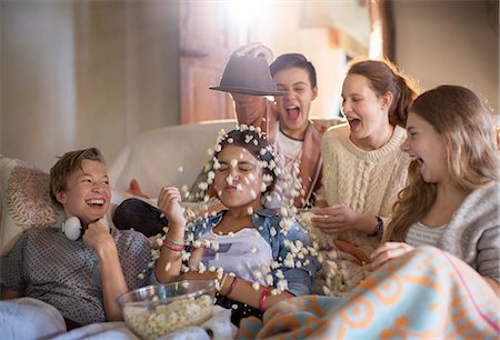 Group of teenagers throwing popcorn on themselves while sitting on sofa Stock Photo - Premium Royalty-Free, Code: 6113-07992004
