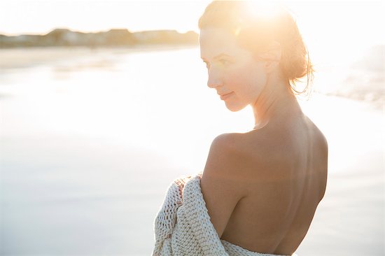 Portrait of young woman wrapped in blanket on beach Stock Photo - Premium Royalty-Free, Image code: 6113-07992036