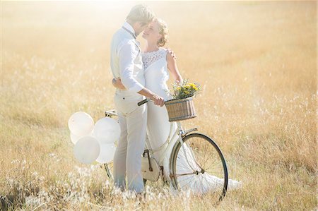 romantic wedding flower - Young couple with bike kissing in meadow Stock Photo - Premium Royalty-Free, Code: 6113-07992164