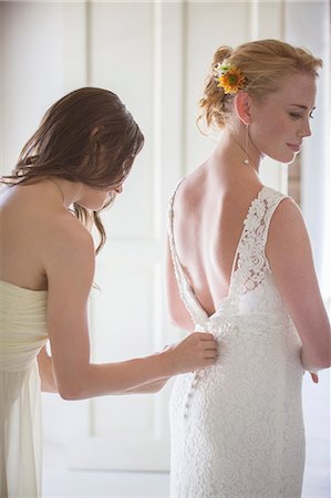 Bridesmaid helping bride with dressing in domestic room Photographie de stock - Premium Libres de Droits, Code: 6113-07992174