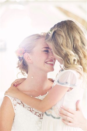 Bride holding bridesmaid in domestic room Stock Photo - Premium Royalty-Free, Code: 6113-07992187