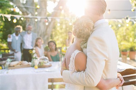 Young couple embracing in garden during wedding reception Stock Photo - Premium Royalty-Free, Code: 6113-07992118