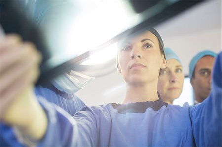 simsearch:6113-07905813,k - Surgeons looking at x-ray during surgery in operating theater Photographie de stock - Premium Libres de Droits, Code: 6113-07905849