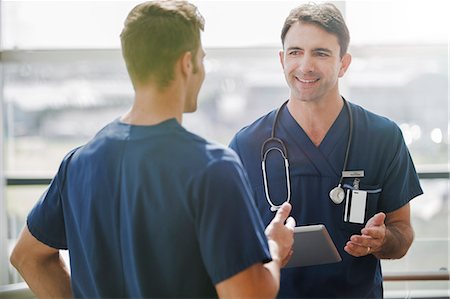 simsearch:6113-07905882,k - Two doctors talking, one holding tablet pc Stock Photo - Premium Royalty-Free, Code: 6113-07905873