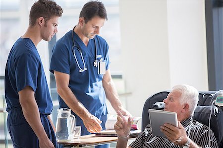 Patient using tablet pc and talking to doctors in hospital Photographie de stock - Premium Libres de Droits, Code: 6113-07905875