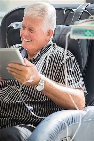 Senior man using tablet pc while receiving intravenous infusion Photographie de stock - Premium Libres de Droits, Code: 6113-07905882