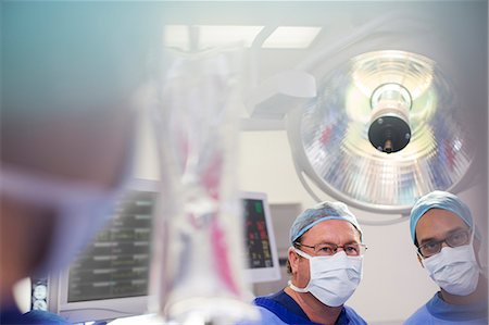 simsearch:6113-07905839,k - Two surgeons looking at saline bag during surgery Stock Photo - Premium Royalty-Free, Code: 6113-07905811