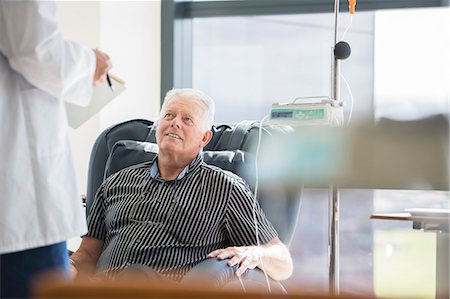 doctor talking to sitting patient - Doctor talking to patient receiving medical treatment in hospital ward Stock Photo - Premium Royalty-Free, Code: 6113-07905837