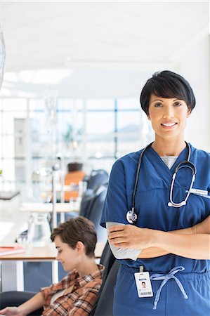 Portrait of doctor with arms crossed, patient undergoing medical treatment in background Stockbilder - Premium RF Lizenzfrei, Bildnummer: 6113-07905965