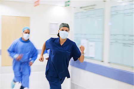 Medical staff wearing scrubs and surgical masks rushing down hospital corridor Stock Photo - Premium Royalty-Free, Code: 6113-07905979