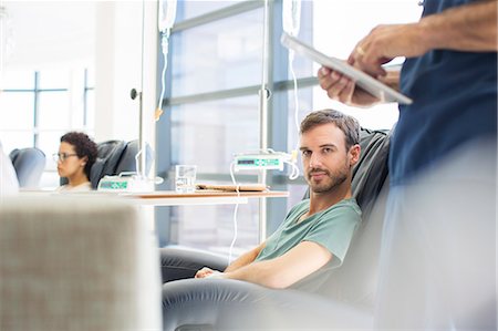 simsearch:6113-07905882,k - Doctor standing next to patient undergoing medical treatment in outpatient clinic Stock Photo - Premium Royalty-Free, Code: 6113-07905988