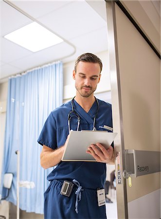 Male doctor standing in doorway, taking notes on clip board in hospital Photographie de stock - Premium Libres de Droits, Code: 6113-07905920