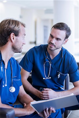 simsearch:6113-07905909,k - Two male doctors with stethoscopes, wearing scrubs talking in hospital Stock Photo - Premium Royalty-Free, Code: 6113-07905930