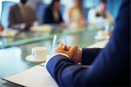 simsearch:6113-07906049,k - Businessman sitting at conference table in conference room with hands clasped Photographie de stock - Premium Libres de Droits, Code: 6113-07906036