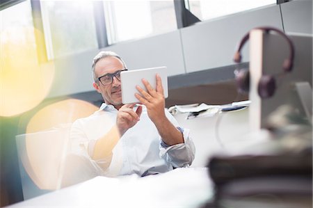 Businessman using digital tablet at office desk Foto de stock - Sin royalties Premium, Código: 6113-07906175