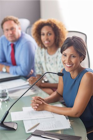 palestra - Beautiful woman sitting at conference table talking into microphone Foto de stock - Royalty Free Premium, Número: 6113-07906114