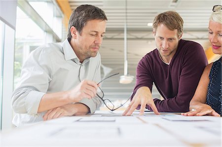 people looking up and pointing - Business people reading paperwork in office meeting Stock Photo - Premium Royalty-Free, Code: 6113-07906258