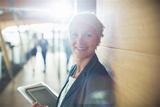 Businesswoman carrying digital tablet in office Photographie de stock - Premium Libres de Droits, Le code de l’image : 6113-07906299