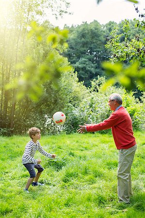 simsearch:6113-07906384,k - Grandfather and grandson playing soccer in grass Stockbilder - Premium RF Lizenzfrei, Bildnummer: 6113-07906382