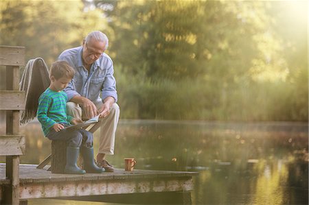 Grandfather and grandson reading at lake Stock Photo - Premium Royalty-Free, Code: 6113-07906393