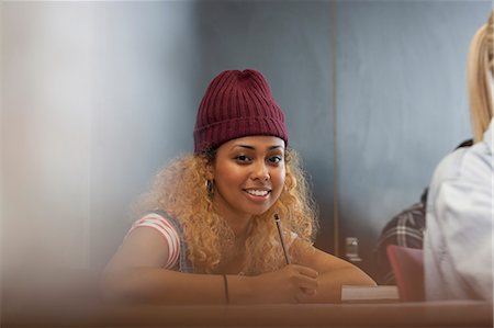 student sitting in classroom - Portrait of smiling female university student writing down notes in classroom Stock Photo - Premium Royalty-Free, Code: 6113-07906444