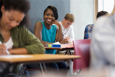 study - Smiling university student sitting at desk with hand on chin Stock Photo - Premium Royalty-Free, Code: 6113-07906473