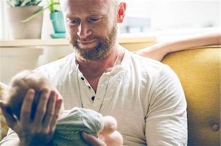 Portrait of father holding baby, sitting on sofa beside mother Photographie de stock - Premium Libres de Droits, Code: 6113-07906420