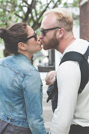 family life with kids - View of couple in sunglasses kissing and holding baby in city streets Stock Photo - Premium Royalty-Free, Code: 6113-07906422