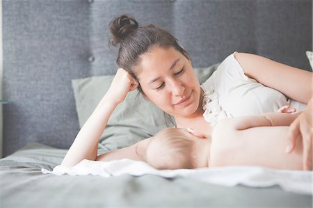 simsearch:6113-07906414,k - Portrait of mother holding baby lying on bed and smiling Stock Photo - Premium Royalty-Free, Code: 6113-07906425