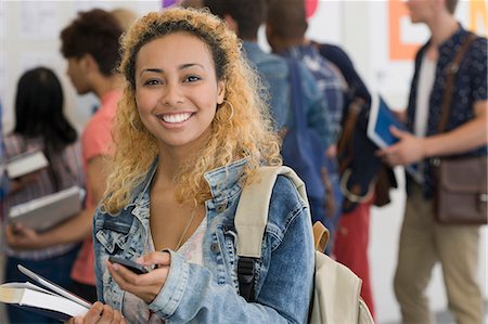 simsearch:6113-07906519,k - Smiling female student using cell phone with other students in background Foto de stock - Sin royalties Premium, Código: 6113-07906517