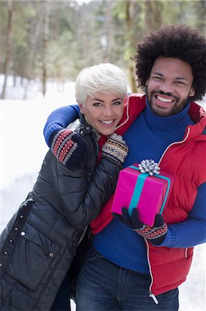 Portrait of couple with Christmas gift hugging in snow Stock Photo - Premium Royalty-Free, Code: 6113-07906664