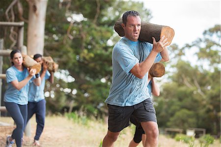 simsearch:6113-07790744,k - Determined man running with log on boot camp obstacle course Foto de stock - Sin royalties Premium, Código: 6113-08087947