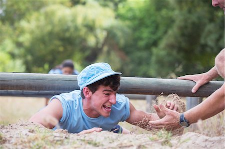 simsearch:6113-08088111,k - Teammate helping man crawling on boot camp obstacle course Photographie de stock - Premium Libres de Droits, Code: 6113-08087955