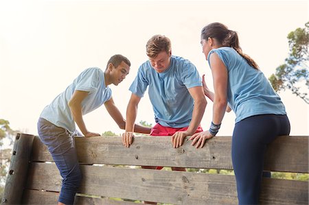 simsearch:6113-07790744,k - Teammates helping man over wall on boot camp obstacle course Foto de stock - Sin royalties Premium, Código: 6113-08087962