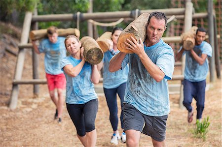 Determined people running with logs on boot camp obstacle course Stock Photo - Premium Royalty-Free, Code: 6113-08087967