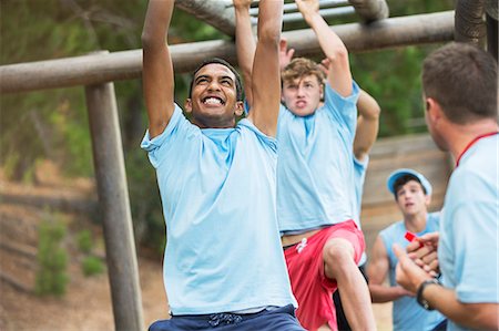 Determined men swinging on monkey bars on boot camp obstacle course Stock Photo - Premium Royalty-Free, Code: 6113-08088054