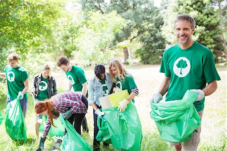 simsearch:6113-08088066,k - Portrait of smiling environmentalist volunteer picking up trash Fotografie stock - Premium Royalty-Free, Codice: 6113-08088058